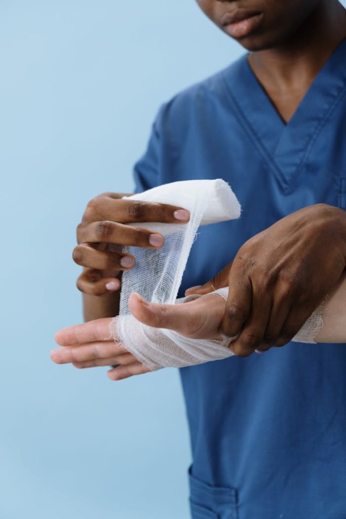 a-person-getting-his-hand-bandaged-5721552 A healthcare professional wrapping a patients hand with gauze for injury care.