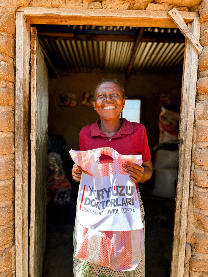 happy-woman-holding-donation-bag-in-rural-doorway-28736220 Happy Woman Holding Donation Bag in Rural Doorway